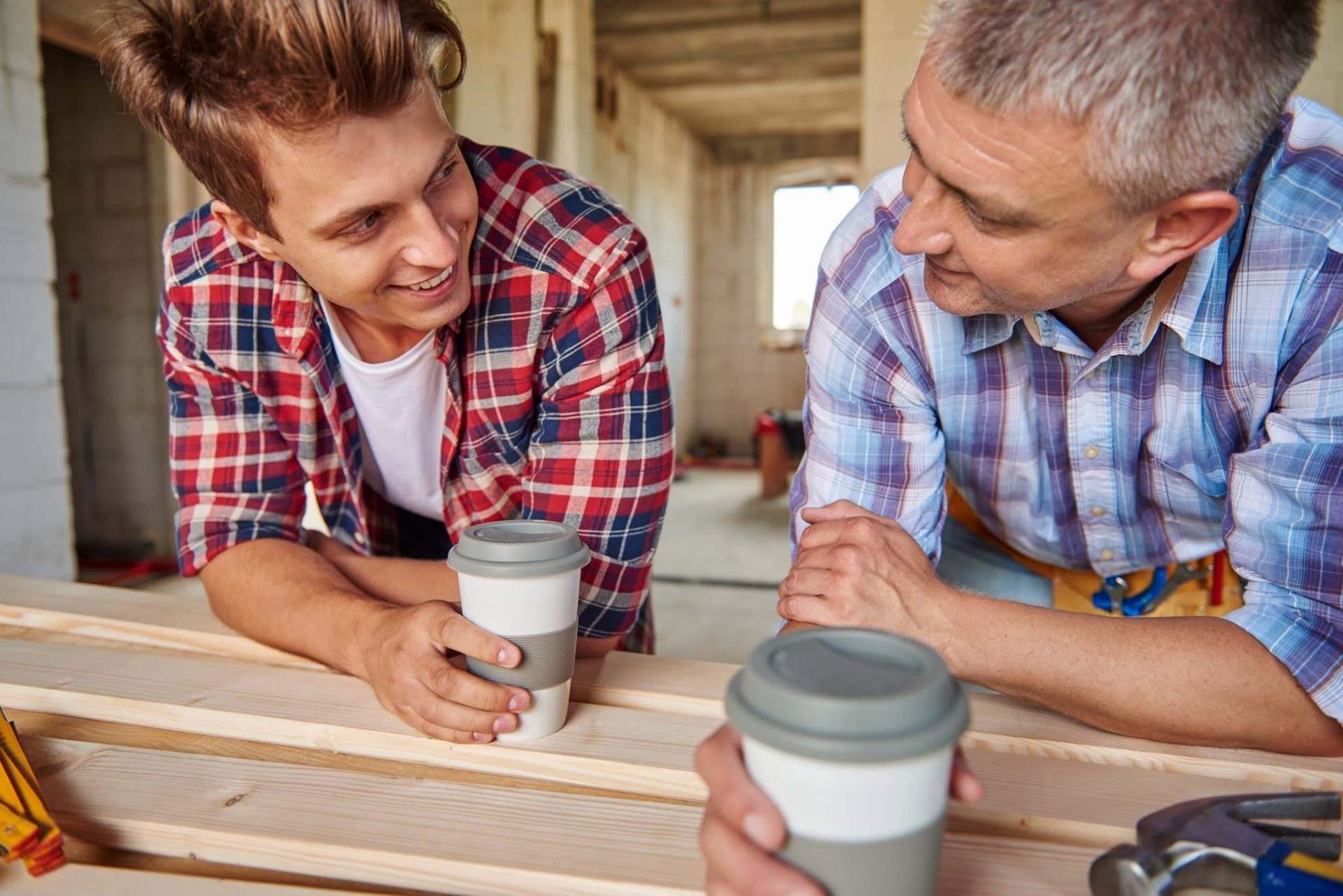 Two men sharing coffee at a workbench